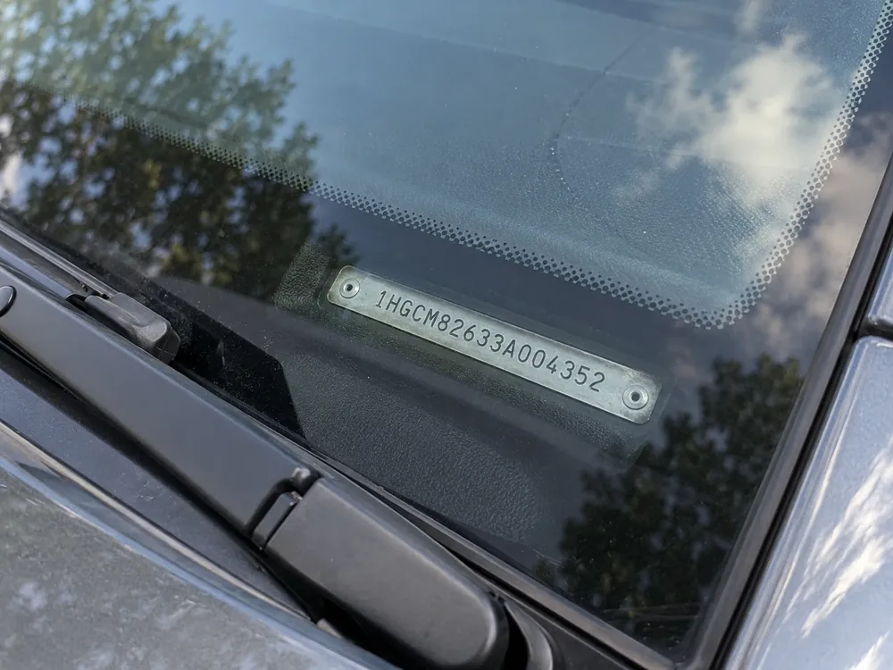 Metal VIN plate on the dashboard, seen through the bottom of the windshield